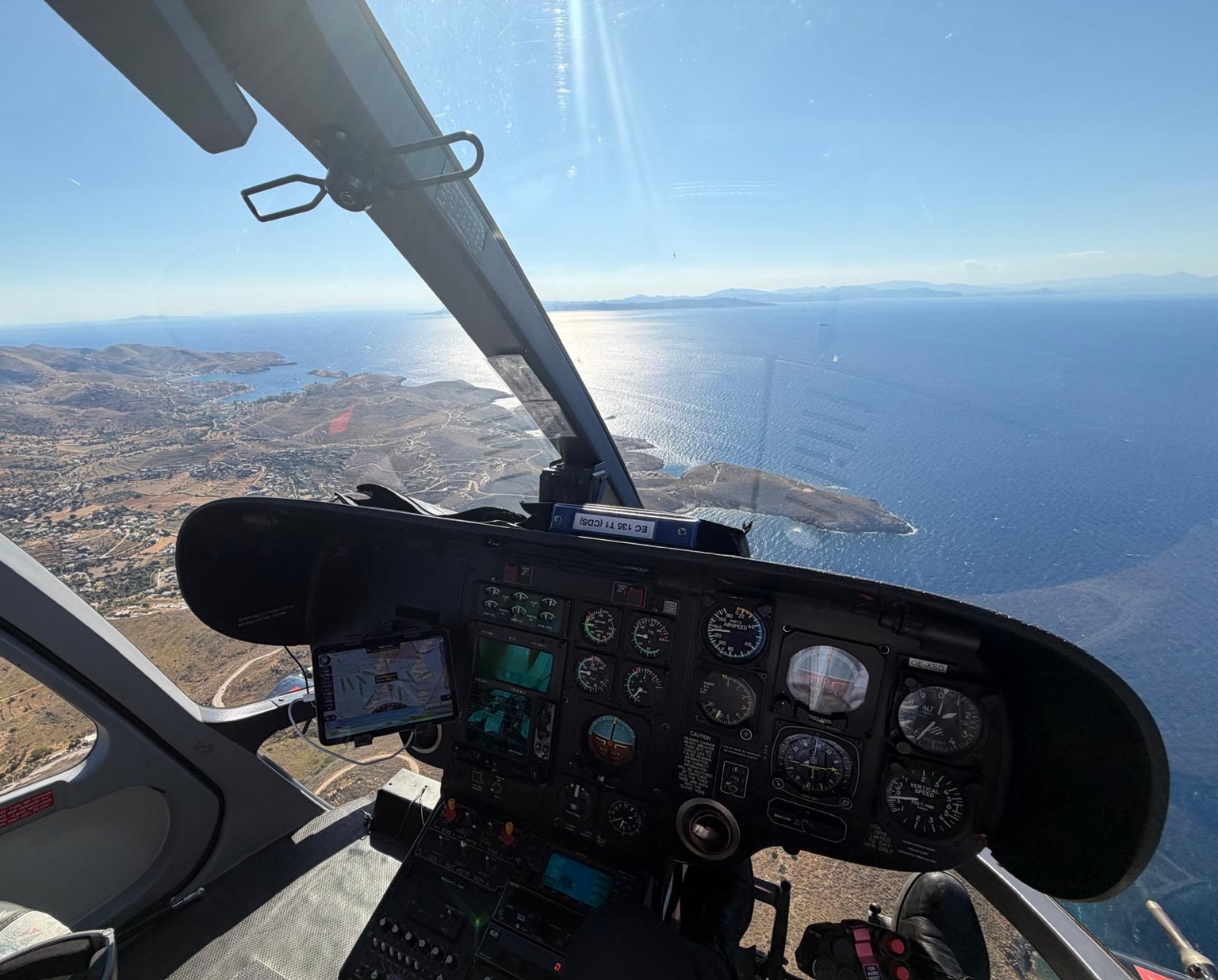 Cockpit view from an Airbus H135 helicopter flying above Kea Island in the Cyclades during a private helicopter transfer from Athens to Mykonos, Greece.