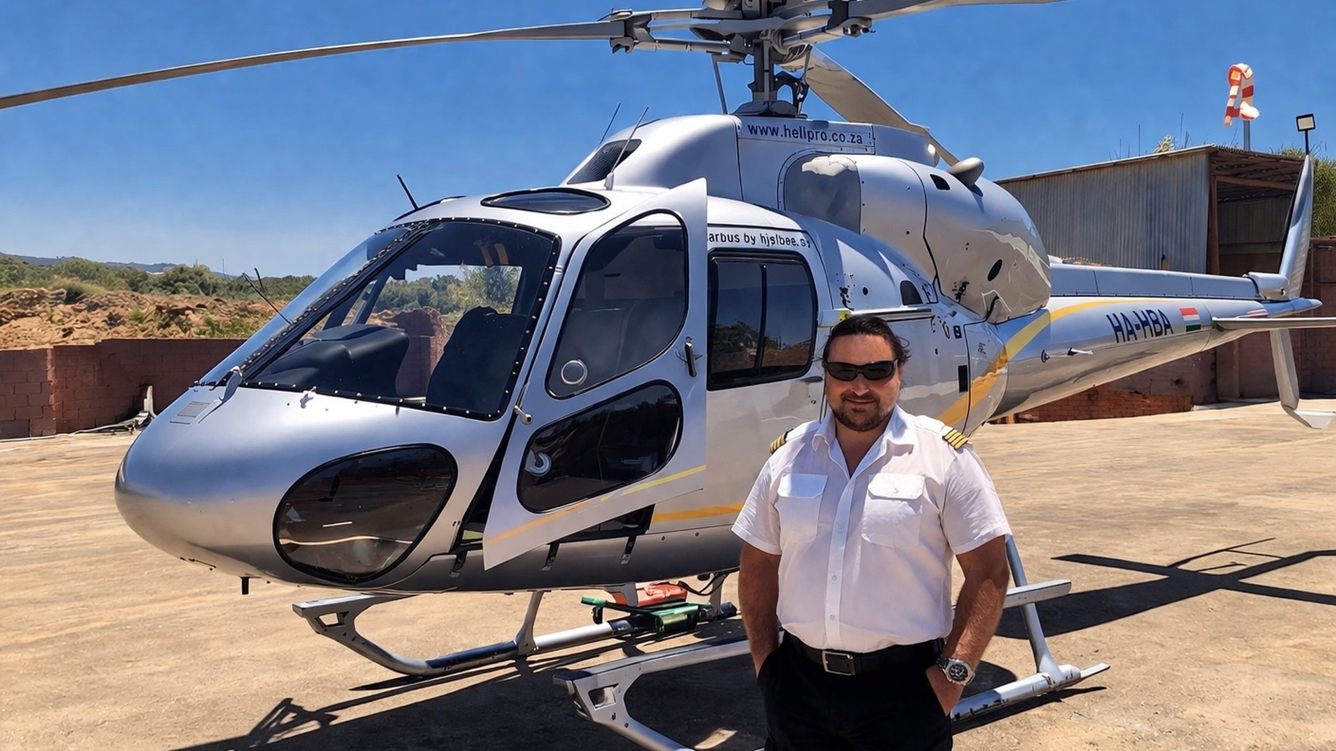 Michael Ganser helicopter pilot with 3000 flight hours standing in front of AS355 twin-engine aircraft during flight operations in Greece